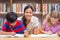 Pretty teacher helping pupils in library