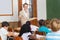 Pretty teacher talking to the young pupils in classroom