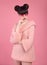 Pretty teen girl in knitted sweater over pink background. Fashion photo teen look style. Brunette with bun hairstyle posing on st