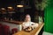 Pretty teen girl sitting at a table in an Asian restaurant, eating sushi rolls on shelves, focused looking and tasty Japanese food