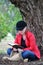 Pretty teenage girl studying holy bible beside huge tree in park