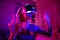 Pretty teenage girl wearing virtual reality headset in a dark room. Cute teen using VR glasses to play a game. Child in virtual