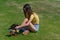 Pretty teenage girl in yellow top sits on grass putting retro style roller skates on