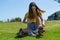 Pretty teenage girl in yellow top sits on grass putting retro style roller skates on