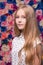 Pretty teenaged blonde portrait on flower wall