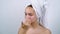 Pretty teenager with acne applying facial cream after bath