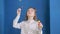 Pretty teenager girl blowing soap bubbles in blue studio. Carefree girl with curly hairtail blowing bubbles soap on blue