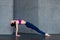 Pretty thin woman in sports bra and leggings doing yoga upward facing plank pose, purvottanasana, working out indoors