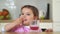 Pretty toddler child eats snack and drink glass of juice. Funny face expression