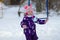 Pretty toddler girl wearing bright colored snowsuit playing on a cold winter day