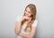 Pretty toothy laughing young woman with fair blond long hair in casual dress holding the head the hands. Studio shot of good