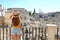 Pretty tourist girl standing on the balcony and looking at cityscape of the southern european city with ancient ruins of Matera,