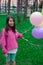 pretty tween teenager brunette girl in pink holding colorful hot air balloons outdoors. party, birthday concept