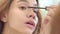 Pretty woman applying black mascara for eyelashes front bathroom mirror
