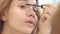 Pretty woman applying black mascara for eyelashes front bathroom mirror