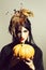 Pretty woman in feather hat holds pumpkin