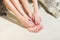 Pretty woman feet with red manicure and pedicure: relaxing on sand.