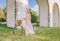 Pretty woman with her bicycle on the bridge aqueduct background in summertime season