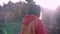 Pretty woman hiker in red jacket with small orange backpack is standing in a woods at early cold morning, breathes