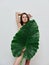 pretty woman holding hand behind head bared shoulders posing palm leaf