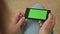 Pretty woman holding in hand smart phone with green screen display