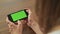 Pretty woman holding in hand smart phone with green screen display