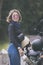 pretty woman holding safety helmet standing beside small enduro motorcycle