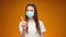 Pretty Woman in medical mask does disapproving gesture with her finger against blue background