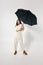 pretty woman with open umbrella in stylish full length jumpsuit  background