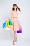 Pretty woman in pink dress shopping multicolored packages studio
