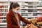 Pretty woman in protective mask chooses vegetables at the grocery store. Shopping during an epidemic. Buyer wearing a protective