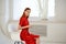 pretty woman in red dress sitting near the window elegant style