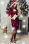 Pretty woman in red dress standing near and christmas tree