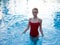 pretty woman in red swimsuit stands in the pool transparent water model