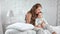 Pretty woman relaxing with cute baby sitting on bed at white bedroom feeling positive emotion