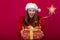 Pretty woman with Santa Claus hat and gift box in her hands. Surprised face and luminous christmas star