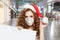 Pretty woman Santa in protective medical mask holding empty signboard in shopping mall. Christmas and New Year sale concept