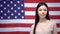 Pretty woman standing against USA flag, migration center, visa for travelling