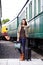 pretty woman with a suitcase and handbag standing near retro railway train