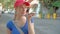 Pretty woman tourist in red cap walking down the street using her smartphone, talking to friend