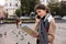 Pretty woman tourist talking on mobile phone while looking at map of the city, surrounded by flying pigeons on a square.