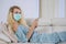 Pretty woman using smartphone with face mask at home