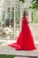 Pretty woman wearing red silky dress standing in pavilion