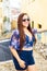 A pretty woman wearing sunglasses with braided hair standing in an old cobbled street