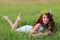 Pretty woman in wreath and short dress lies in grass on