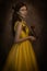 Pretty woman in the yellow long dress closeup with red rose in her hands. Beauty and the beast cosplay