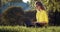 Pretty woman in yellow sweater sitting on grass with laptop