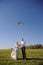 Pretty young adult wedding couple walking on field with kite