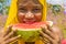 pretty young african lady enjoying a delicious slice of watermelon fruit outside