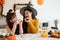 A pretty young Asian girl in a Halloween costume enjoys eating doughnuts with her mom in the kitchen